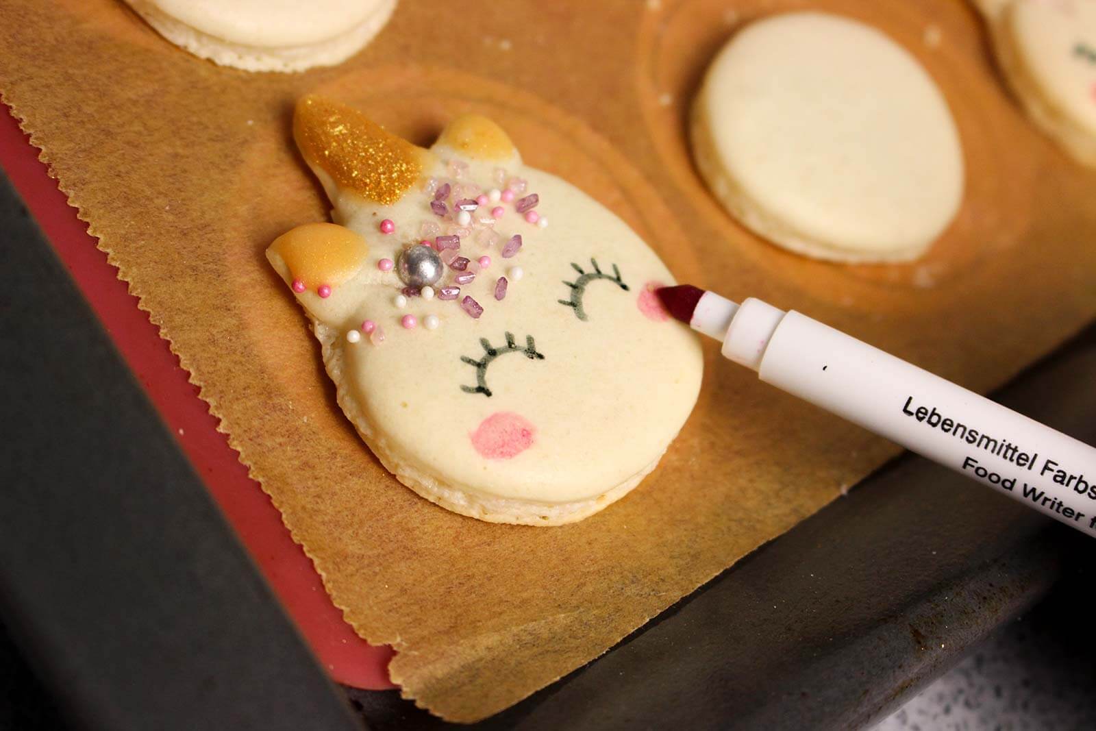 Macarons werden mit Lebensmittelstift bemalt.